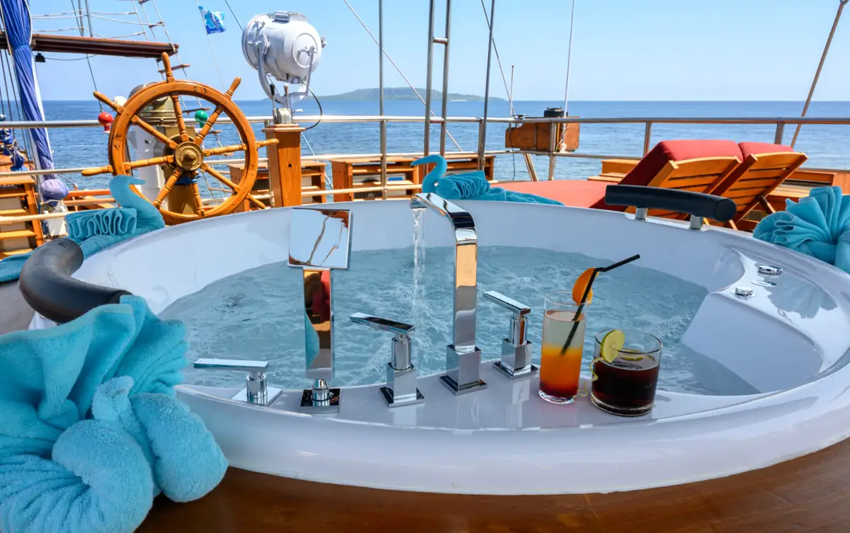 Jacuzzi on Cheng Ho yacht with ocean view, sun loungers, and cocktails on deck.