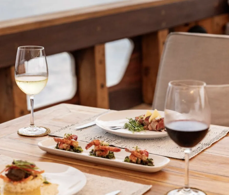 Fine dining setup with gourmet appetizers and wine on deck of Prana by Atzaro yacht.