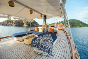 Cozy lounge deck on Samara I phinisi yacht with ocean views and colorful pillows.